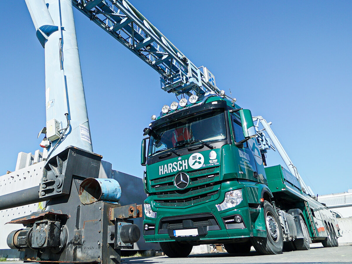 Autokran mit Firmenfahrzeug der Harsch‑Gruppe beim Einsatz auf einem Industriegelände.